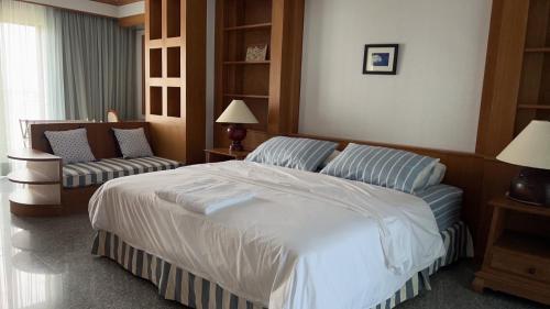 a bedroom with a large white bed and a couch at Sunshine Gypsy at Beach Villa Vibhavadi Pattaya in Na Jomtien