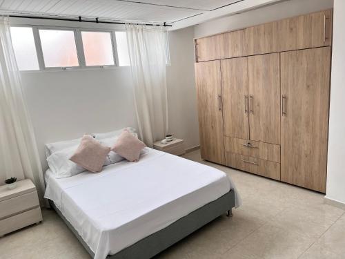 a bedroom with a white bed and a wooden cabinet at Apartamento en Cali - Cuarto de Legua in Cali
