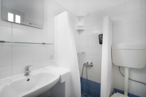 a white bathroom with a sink and a toilet at ISALOS ROOMS ON THE BEACH in Serifos Chora