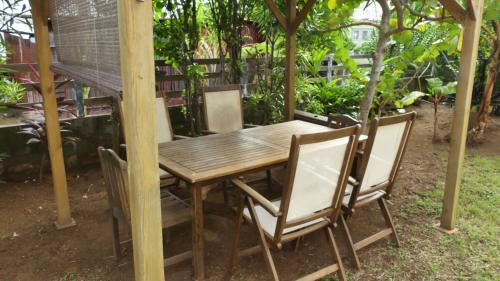 a wooden table and chairs in a garden at Le Colibri et le Frangipanier in La Trinité
