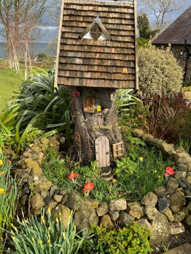 a small house in a garden with flowers at The Barn at BallyCairn in Larne