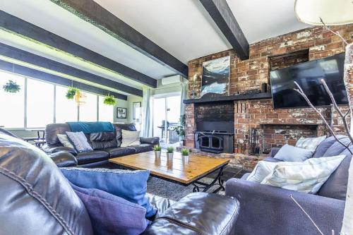 a living room with leather furniture and a brick wall at Mountain View-Backyard-Air-Conditioning-BBQ-15mins walk Blue Mountain Village in Blue Mountains