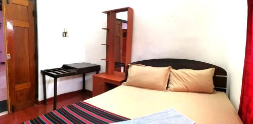 a bedroom with a bed and a desk with a piano at Nallur Holidays Inn in Jaffna