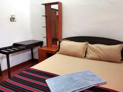 a bedroom with a bed and a table and a chair at Nallur Holidays Inn in Jaffna