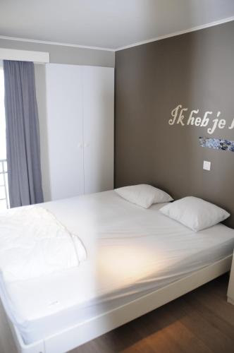 Bett mit weißer Bettwäsche und Kissen in einem Zimmer in der Unterkunft Scorpio 0702 in Nieuwpoort