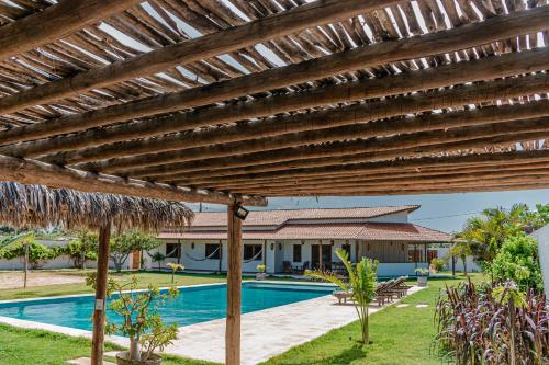 a wooden pergola over a swimming pool in front of a house at Vila Tao in Fortim