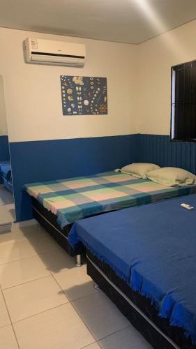 two beds in a room with a blue wall at Privê estrela in Porto De Galinhas