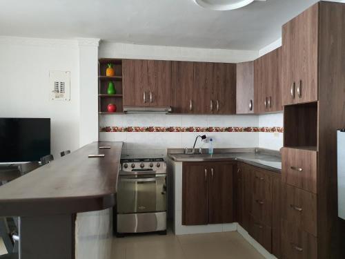 a kitchen with wooden cabinets and a sink and a stove at Kiosco Azul - Apartamento amoblado cerca al mar in Ríohacha