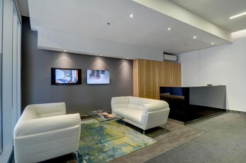 a living room with two white chairs and a tv at Les Immeubles Charlevoix - Le 760-507 in Quebec City