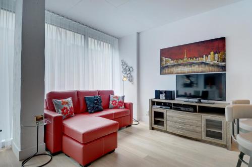 a living room with a red couch and a flat screen tv at Les Immeubles Charlevoix - Le 760-507 in Quebec City
