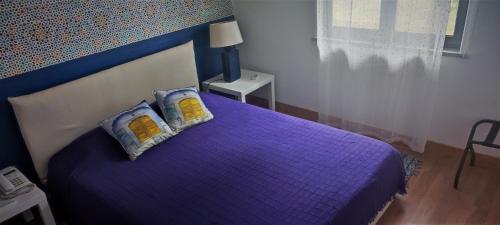 een slaapkamer met een paars bed met 2 kussens bij Santo António's Guesthouse in Cascais