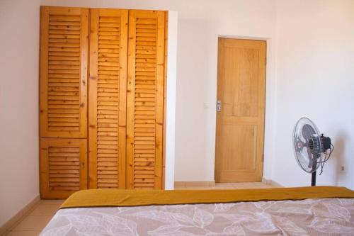 a bedroom with a bed and two wooden doors at Cosy & Relax Yellow House 5mn walk from the beach! in Calheta Do Maio