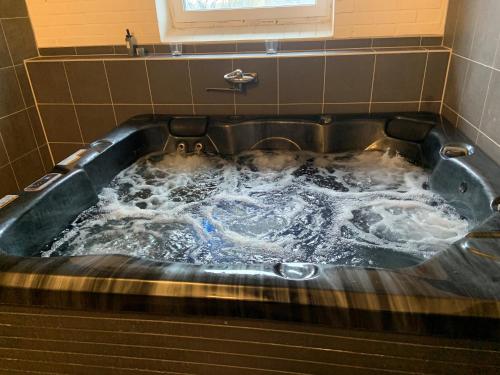 a bath tub filled with water in a bathroom at Alingsgård - B&B, Gårdshotell, Spabad, Bastu, Gym, Padelbana in Löderup