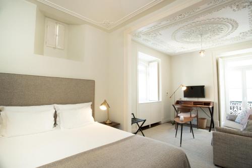 Schlafzimmer mit einem Bett, einem Schreibtisch und einem TV in der Unterkunft Hermitage Castelo - Casa Chafariz in Lissabon