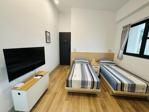 two beds in a room with a flat screen tv at Oceans Explore Hostel in Green Island