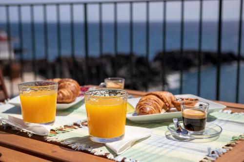 a table with orange juice and croissants and bread at Casa do Ilhéu - House of Ilhéu - Câmara de Lobos in Câmara de Lobos