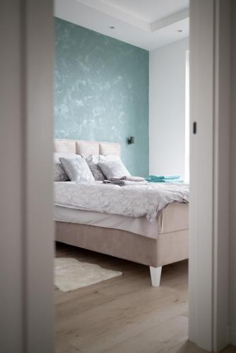 a bedroom with a bed with a blue wall at Apartman Maja Lux in Subotica