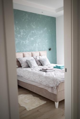 a bedroom with a bed with a green wall at Apartman Maja Lux in Subotica