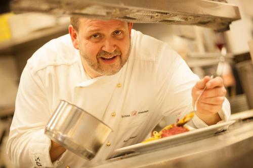 a man in a chef's outfit preparing food in a kitchen at Hotel Schloss Rheinfels in Sankt Goar
