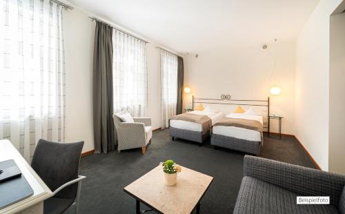 a hotel room with two beds and a couch and a table at Angel's - das hotel am fruchtmarkt in Sankt Wendel
