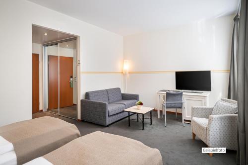 a hotel room with a bed and a chair and a tv at Angel's - das hotel am fruchtmarkt in Sankt Wendel