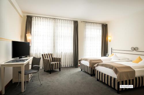 a hotel room with two beds and a desk and a computer at Angel's - das hotel am fruchtmarkt in Sankt Wendel