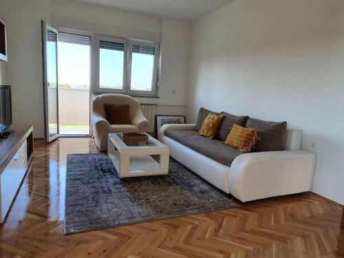 sala de estar con sofá blanco y silla en Apartman Dukat Vukovar en Vukovar
