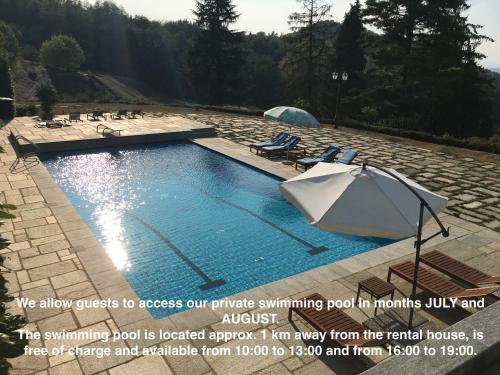 a swimming pool with two lawn chairs and an umbrella at Maison des Roses - Family Farm in Bossolasco