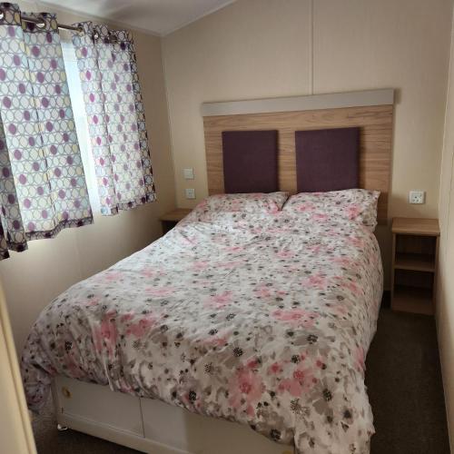a bedroom with a large bed with a floral bedspread at Family only 4 Bedroom Caravan in Skegness