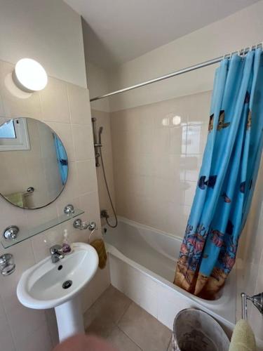 ein Bad mit einem Waschbecken und einem Duschvorhang in der Unterkunft The Holiday Flat, gateway to desired experiences in Peyia
