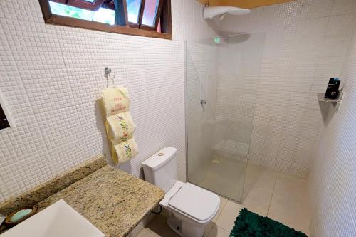 uma casa de banho com um WC e uma cabina de duche em vidro. em Casa Vilacentro - Imbassaí em Imbassaí
