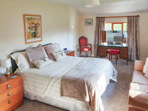 a bedroom with a bed and a desk and a chair at Kiln Green Farmhouse in Milnthorpe