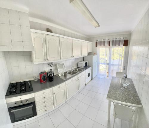 a kitchen with white cabinets and a counter top at Charming Salema in Salema