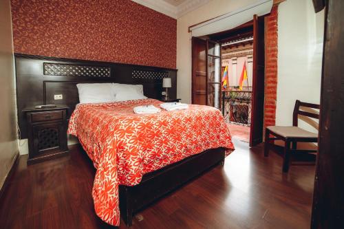 Schlafzimmer mit einem Bett mit einer roten und weißen Decke in der Unterkunft Gran Hotel París in Cuenca