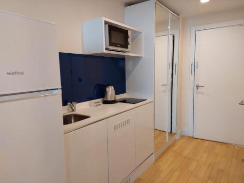 a white kitchen with a sink and a microwave at lux apartments orbi city in Angisa