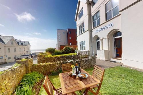 a wooden table and chairs in front of a building at WOOLACOMBE HIBISCUS 2 Bedrooms in Woolacombe