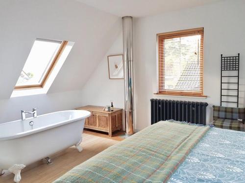 1 dormitorio con bañera, cama y ventana en Baltinna West - by Where Stags Roar en Newtonmore