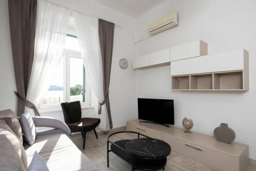 a white living room with a couch and a tv at Apartment Val with sea view in Šibenik