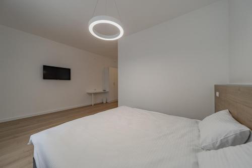 1 dormitorio con 1 cama blanca y TV en BG Exclusive Suites en Belgrado
