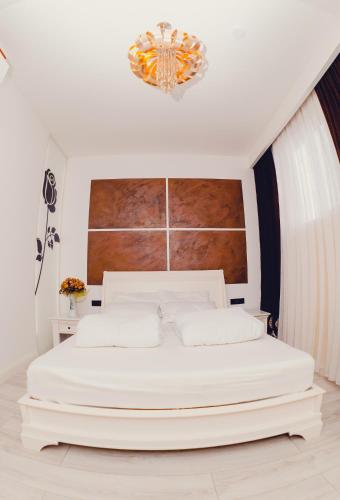 a bedroom with a large white bed with a chandelier at Casa Del Sole in Alba Iulia