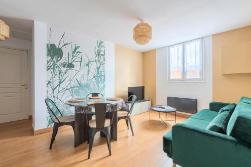 ein Wohnzimmer mit einem Tisch und einem grünen Sofa in der Unterkunft Le Cottage du Louvre in Lens