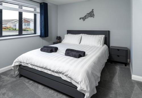 a bedroom with a large bed with two towels on it at Modern new build, Close to the beach and town in Bude