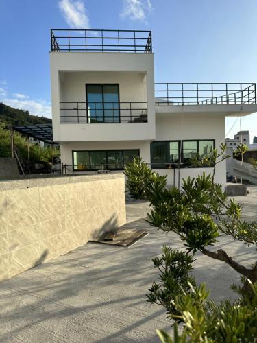 a white house with a balcony on top of it at Oceans Explore Hostel in Green Island