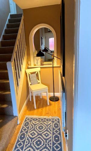 a hallway with a chair and a staircase with a mirror at Cheerful and Cosy Double Room in Belfast