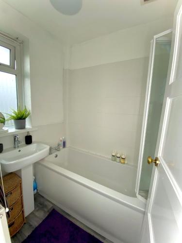 a white bathroom with a tub and a sink at Cheerful and Cosy Double Room in Belfast