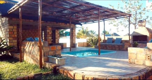 a patio with a swimming pool and a wooden pergola at Venha Juntos Guest Homes in Miramar