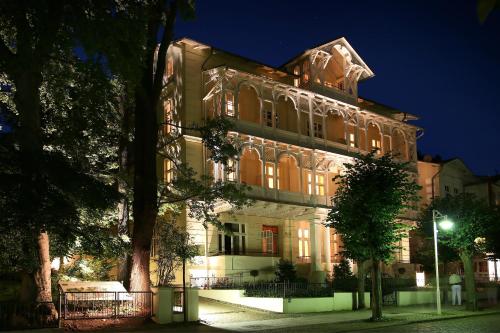 a large building at night with a tree in front at ROEWERS Privathotel & Spa in Ostseebad Sellin