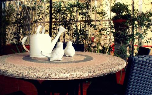 two white cats sitting on a table with a tea pot at B&B Elisir in Albenga