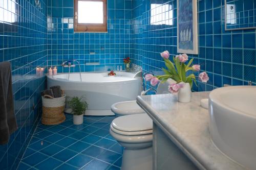 a blue tiled bathroom with a toilet and a bath tub at Donna Rachele in Aci Castello