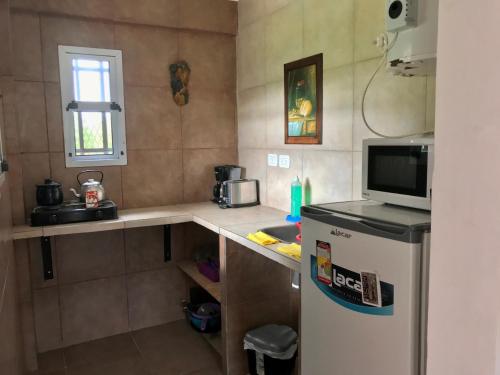 a small kitchen with a refrigerator and a microwave at Bendito Alcázar Cabañas in Colón